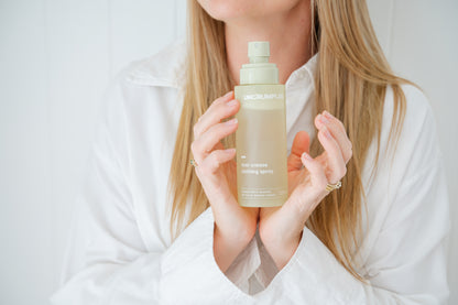 Person holding a regular-sized Uncrumpled anti-crease spray bottle with its cap off